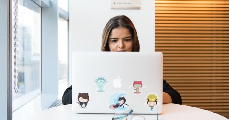 Female Software Developer looking at a laptop covered in stickers