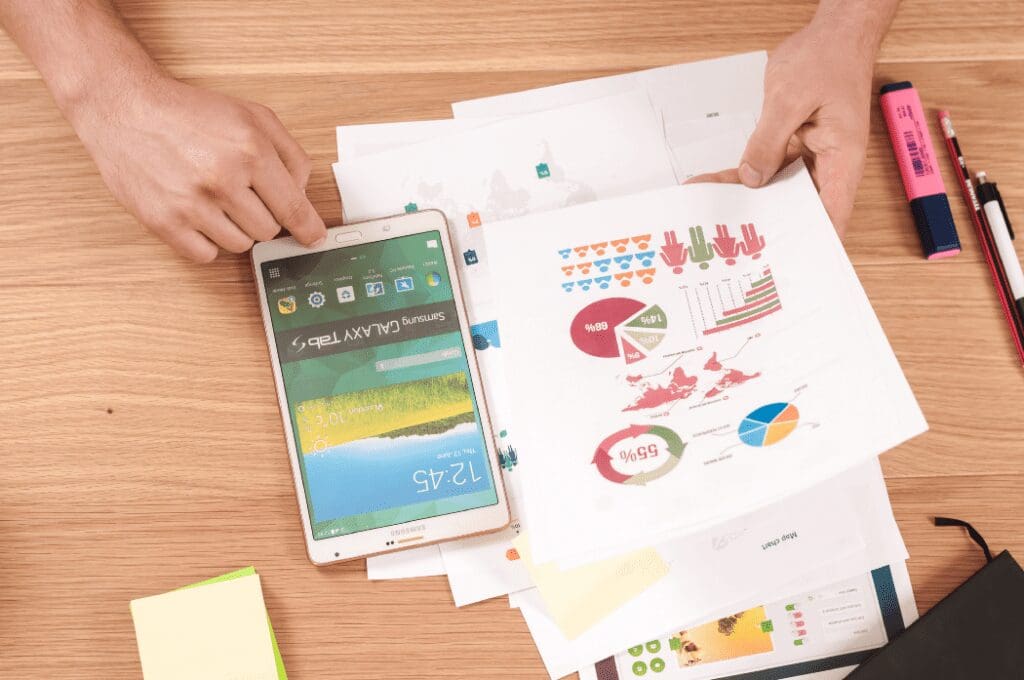 Looking down on a desk with Samsung Galaxy Tablet and paperwork with graphs. Engineering Manager