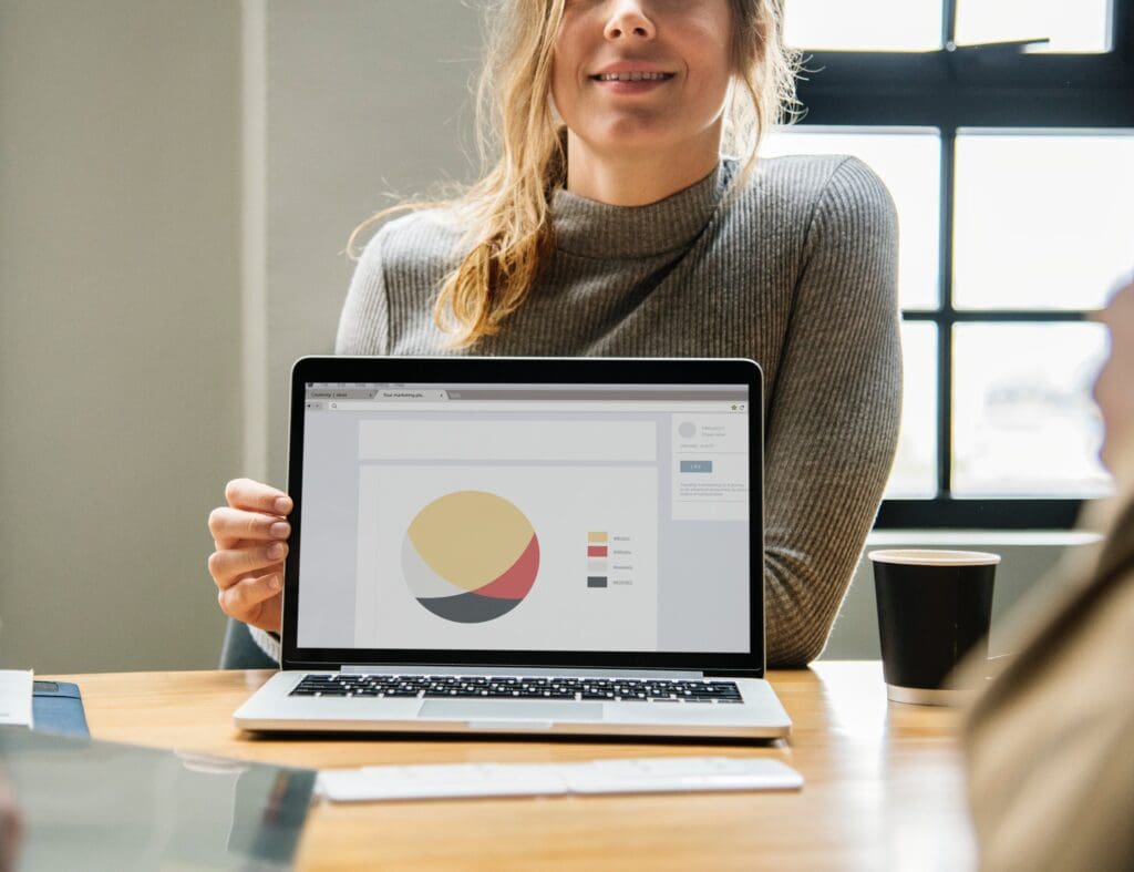 Woman showing pie chart on a laptop during office meeting, Data Scientist