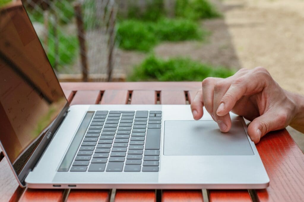 Close up of a hand using a laptop in the garden