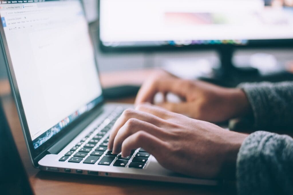 Close up of woman's hands typing on a laptop