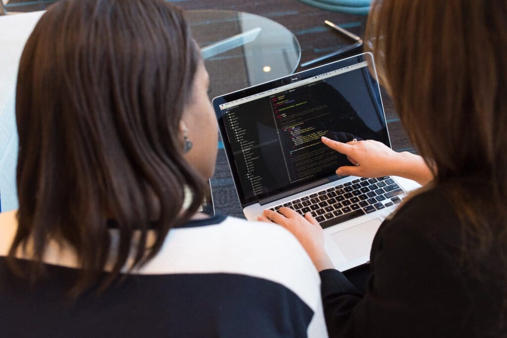 Two female Software Engineers looking at code on a laptop, software engineer