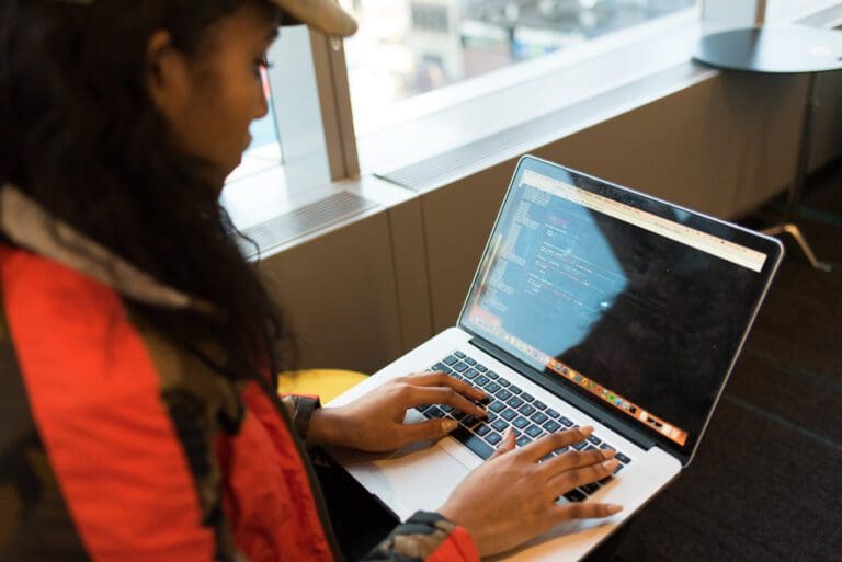 Woman using a Macbook Pro to code, career development
