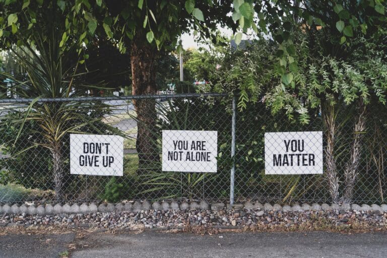 Signs hung on a wire fence saying 'Don't Give Up', 'You Are Not Alone' and 'You Matter', Empathy Concept