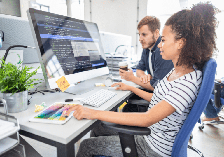 Female UX Designer building a website with her colleague on a Mac