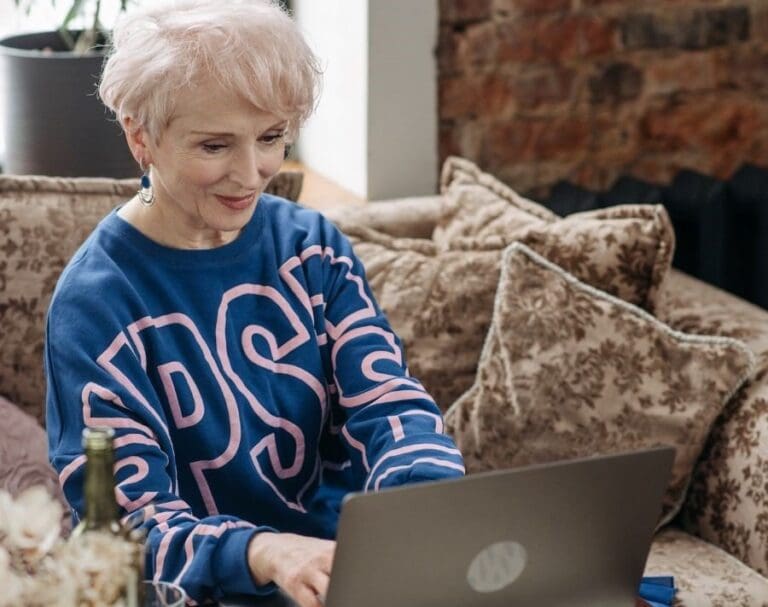 Photo of an Elderly Woman Typing on Her Silver Laptop, Over 50s woman working in tech