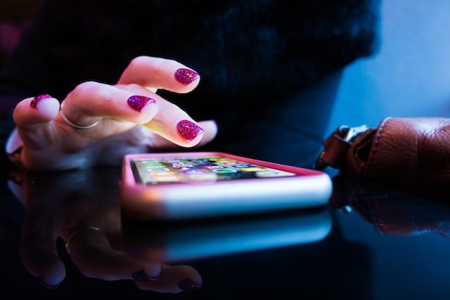 Woman with glittery painted nails looking at apps on her phone