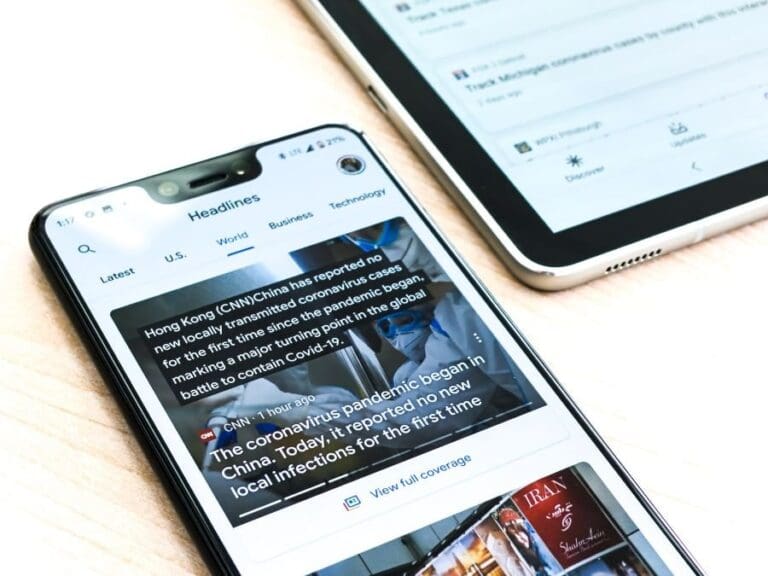 A Google pixel 3XL showing Covid-19 information from the Google News app sits on a wooden table next to a Samsung Galaxy Tablet, tech news