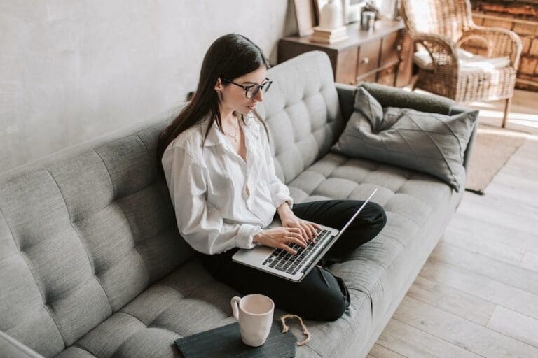 Woman working from home on sofa with laptop.