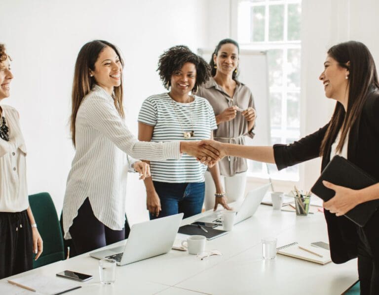 Women shake hands across conference table