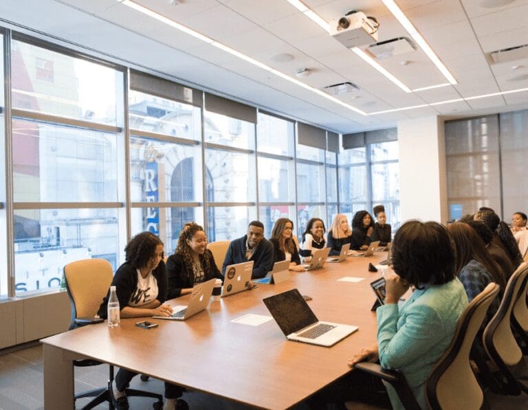 Group of ethnic and gender diverse senior leaders gathered around a boardroom in an office