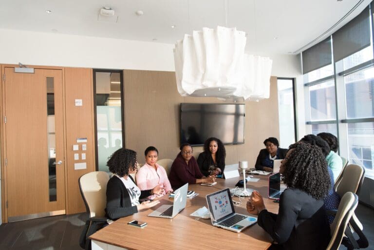 Group of diverse senior leaders in tech gathered around a boardroom, women in tech concept