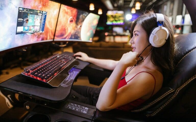 Woman gamer in gaming chair with curved screens and specialist keyboard