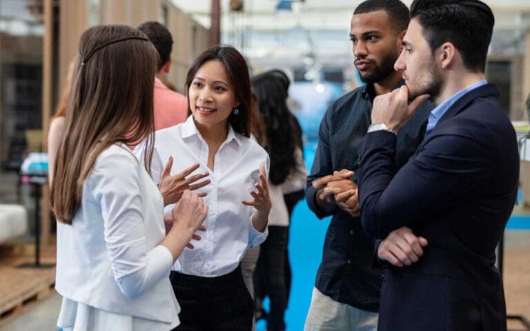 Asian woman wearing a white shirt networking with a diverse group of people