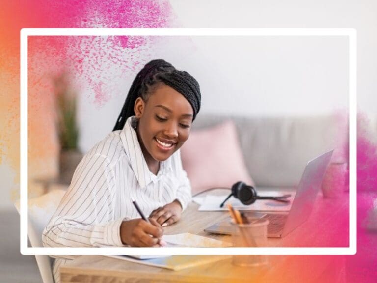 Black woman wearing a striped shirt sitting at her desk studying with an open laptop in front of her