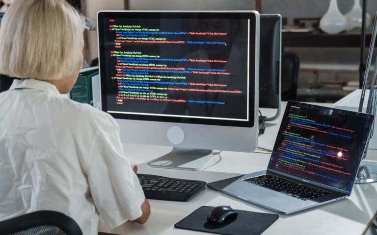 Blonde woman writing code on a Mac