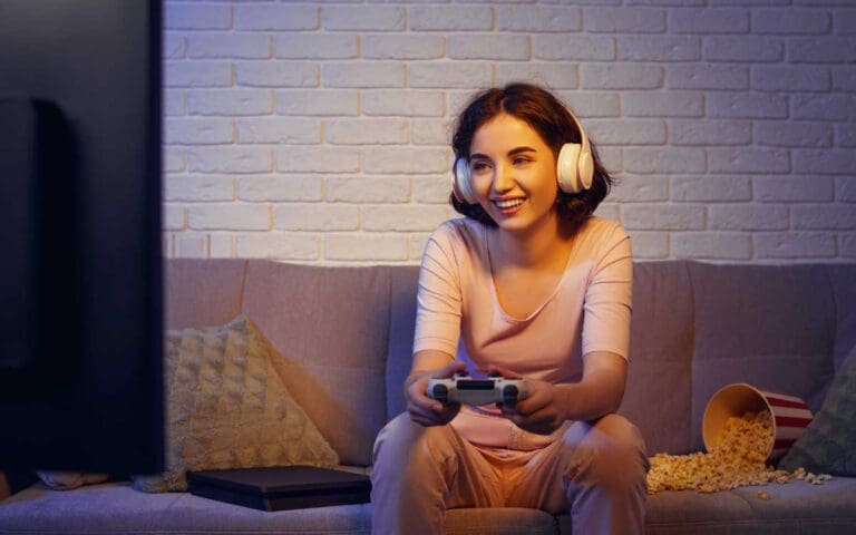 Woman on sofa with headphones holding game controller