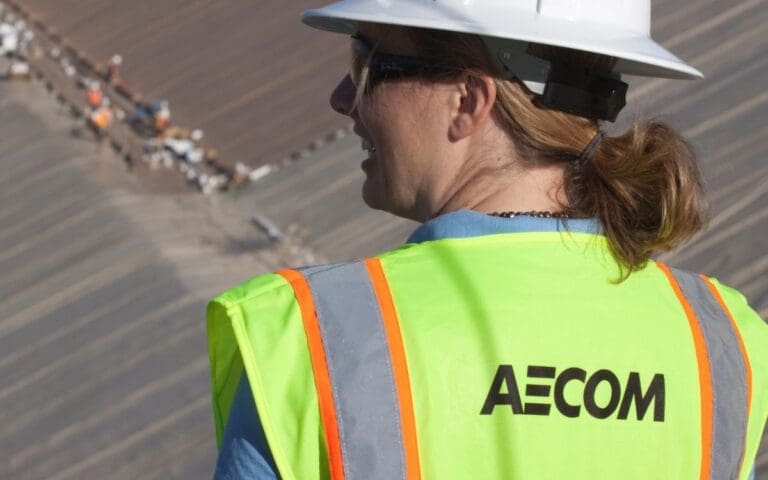Female returner wearing a hard hat and hi-vis jacket with AECOM written on the back