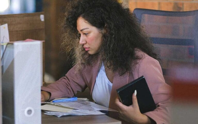 Focused female employee reading documents during work in office, systems analyst