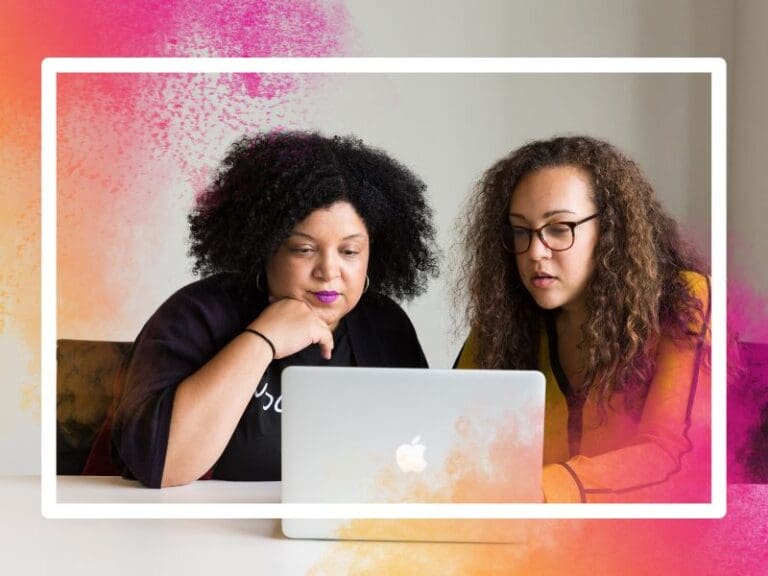 Two women looking at a laptop on a desk in a mentoring session, mentoring programmes for women
