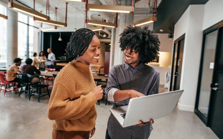 Two Black Tech Start-Up founders looking at a laptop in an office