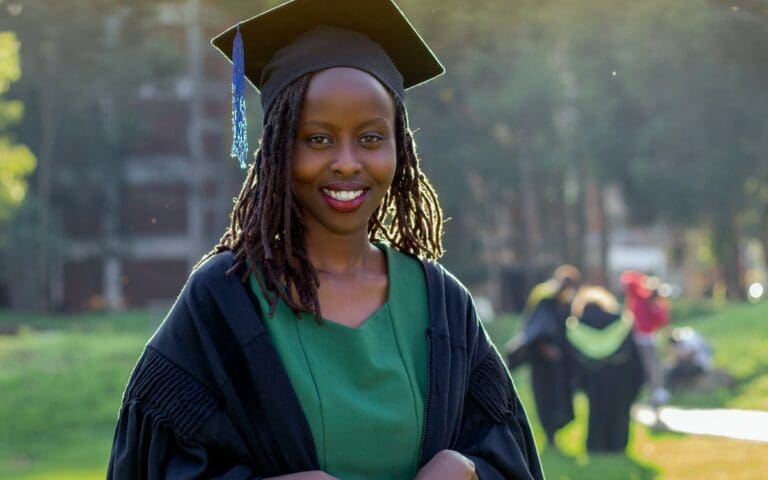 Black woman wearing a gap and gown celebrating her graduation
