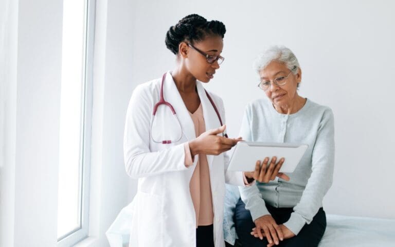 Black female doctor showing digital tablet to senior patient