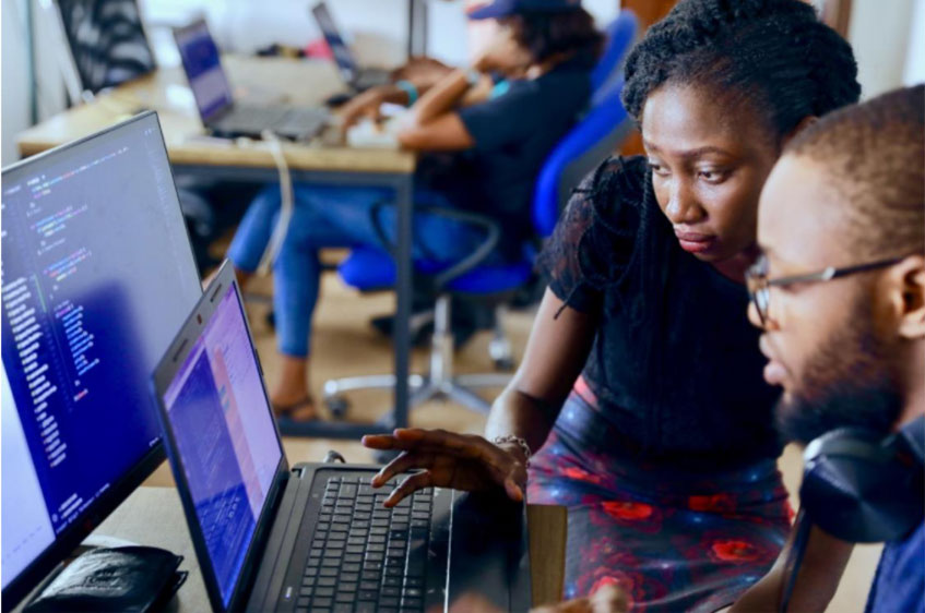 Woman working with colleague on laptop reviewing code