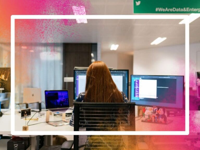 Rear view of woman sitting at her desk working on three screens