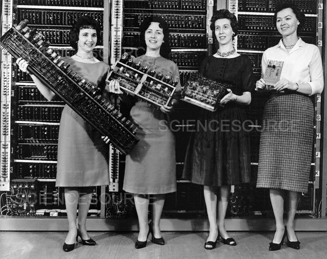 Historical image of four women holding valve sets in front of a large computer (black and white image)