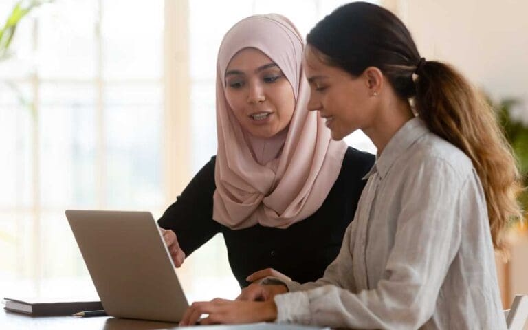 Asian muslim female mentor teaching caucasian intern explaining computer work, mentorship concept
