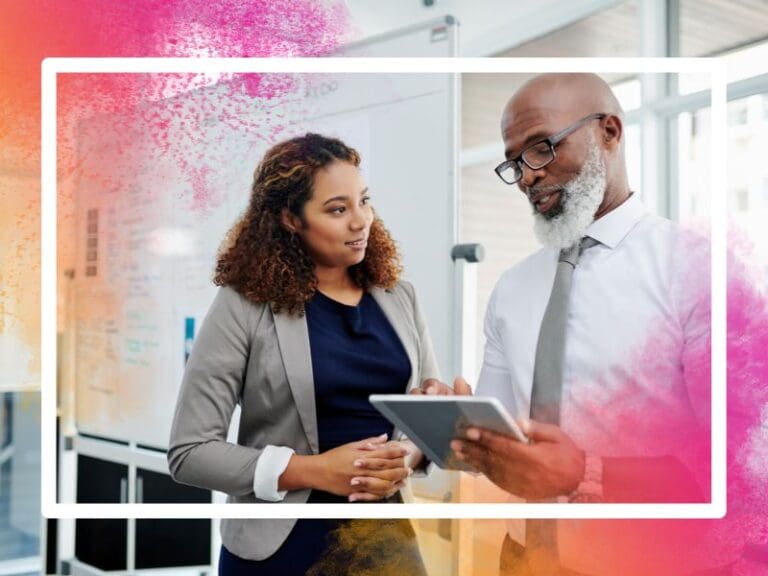 Male manager mentoring a female employee working at her desk on a laptop