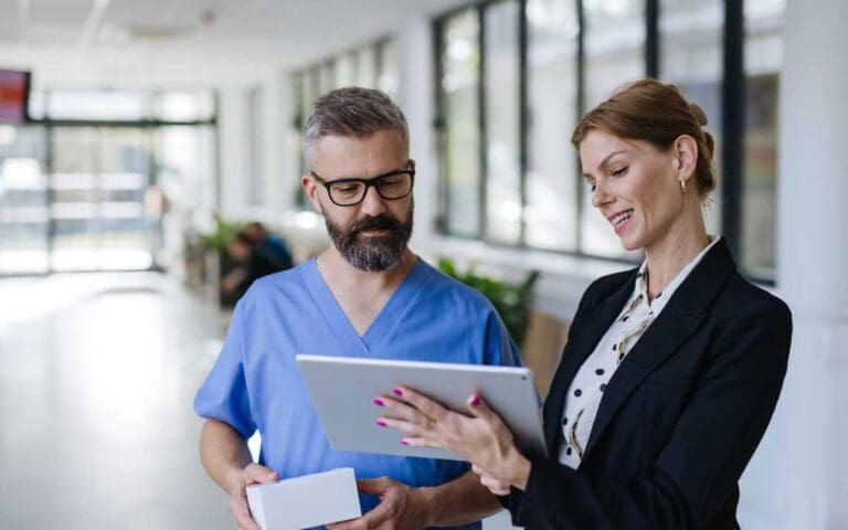 Female leader in healthcare, talking to a man wearing blue scrubs, female leadership