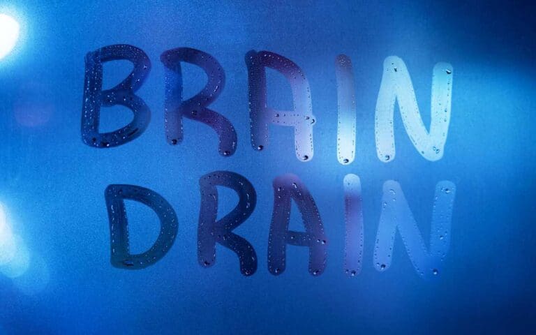 the words brain drain written on night wet window glass close-up with blurred background in classic blue color