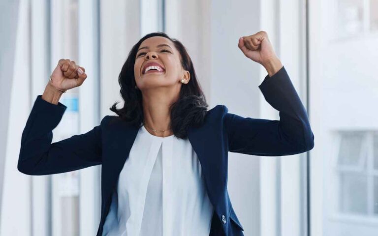 Shot of a young woman in an office celebrating, success concept