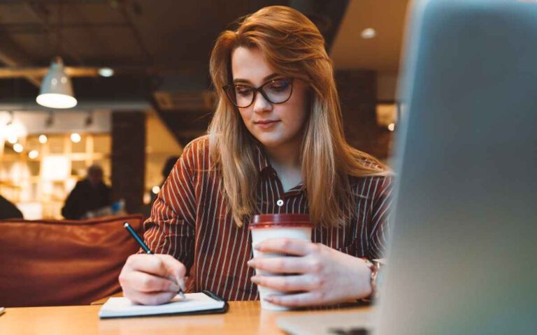 Woman working in a coffee shop holding a takeaway coffee cup, diversity and inclusion