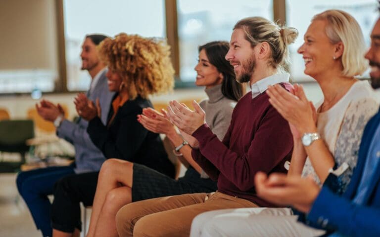 Excited audience clapping in a meeting, championing women concept