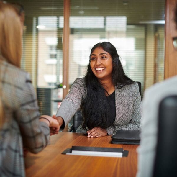 Woman shaking hands with interviewer after finding a job post on SheCanCode