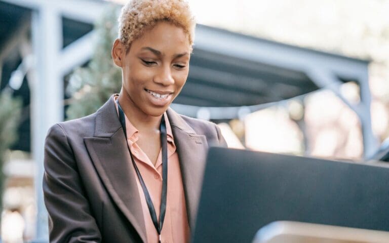 Smiling black woman using laptop for searching information, tech roles concept