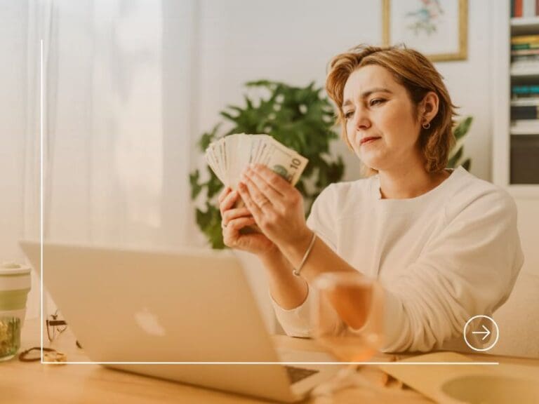 Woman Sitting in Front of a Laptop and Holding a Bunch of Cash, pay rise concept