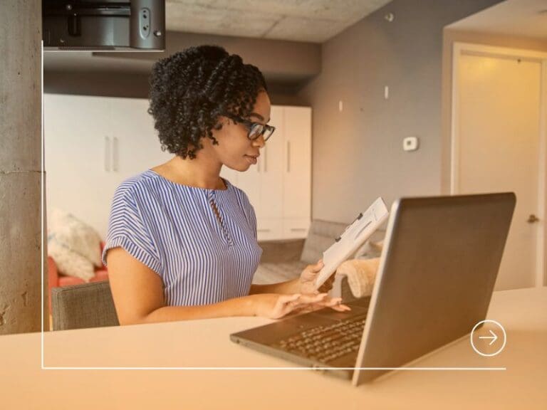 Young African American woman working on a laptop in an office, tech background concept