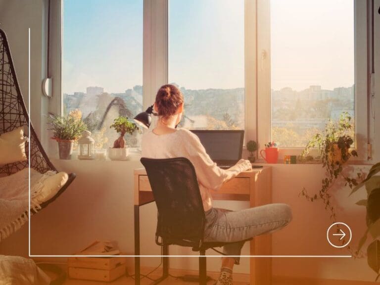 Rear view of young woman working at her desk with laptop, remote-first working concept