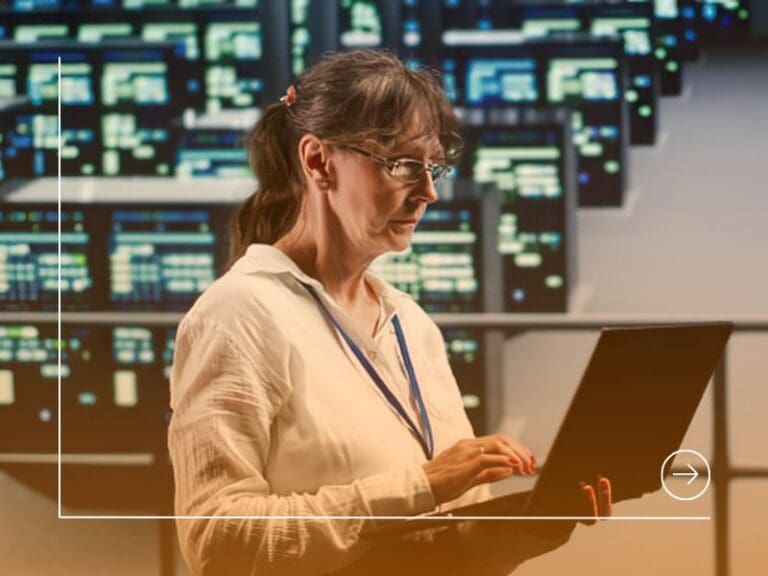 Woman working on laptop in tech control room, career in tech concept
